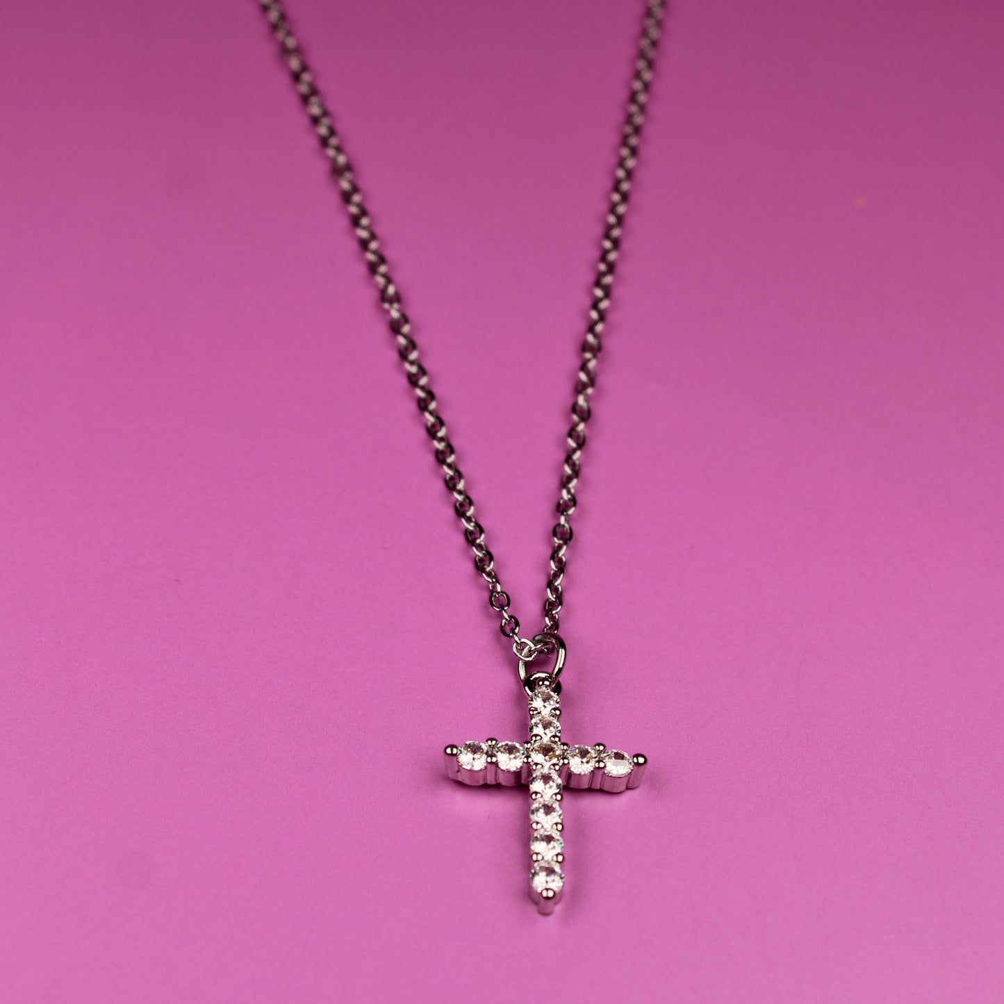 Necklace with a cross pendant on a pink background