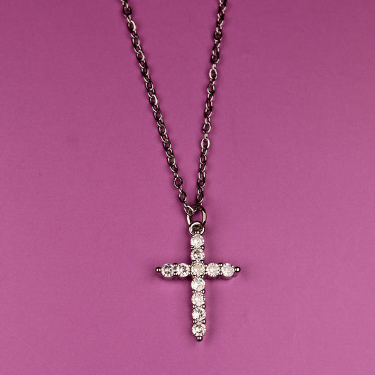 Cross-shaped pendant on a chain against a pink background