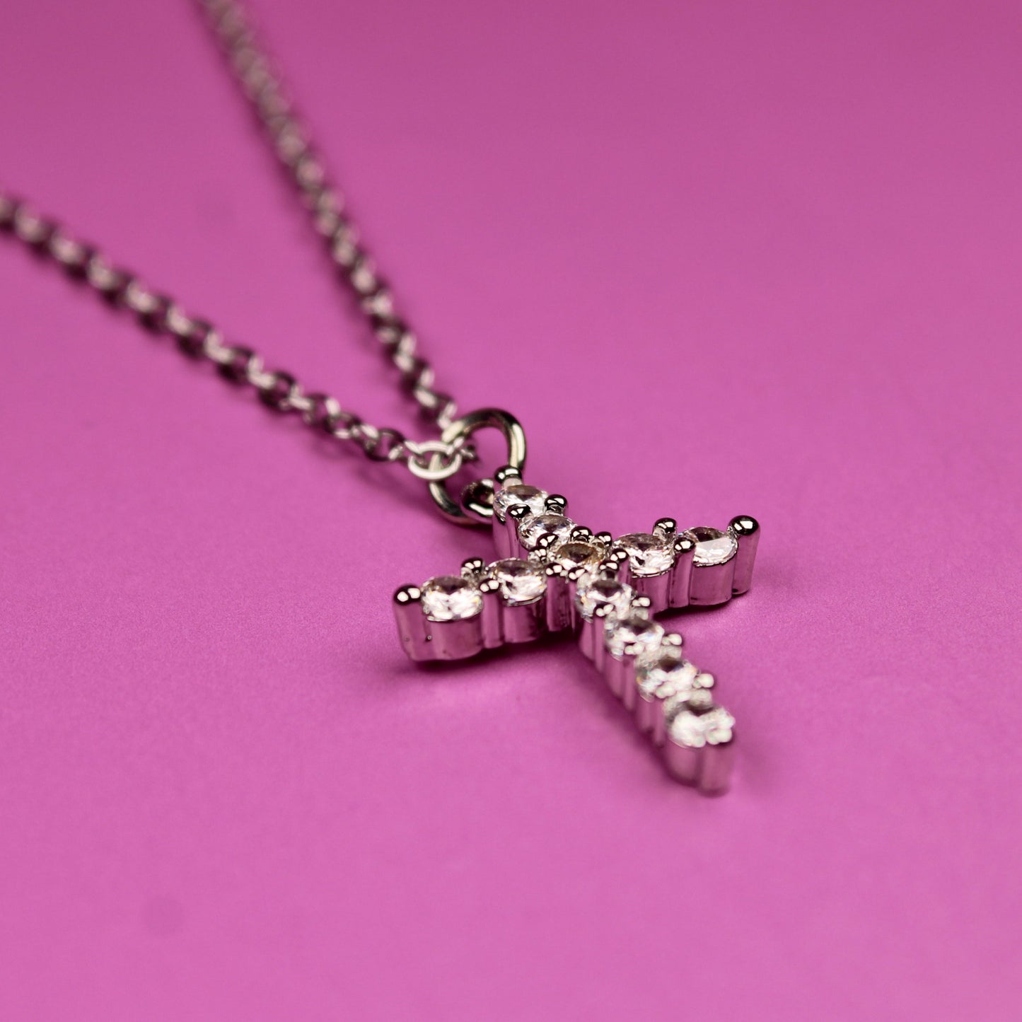 Pink cross necklace on a pink background