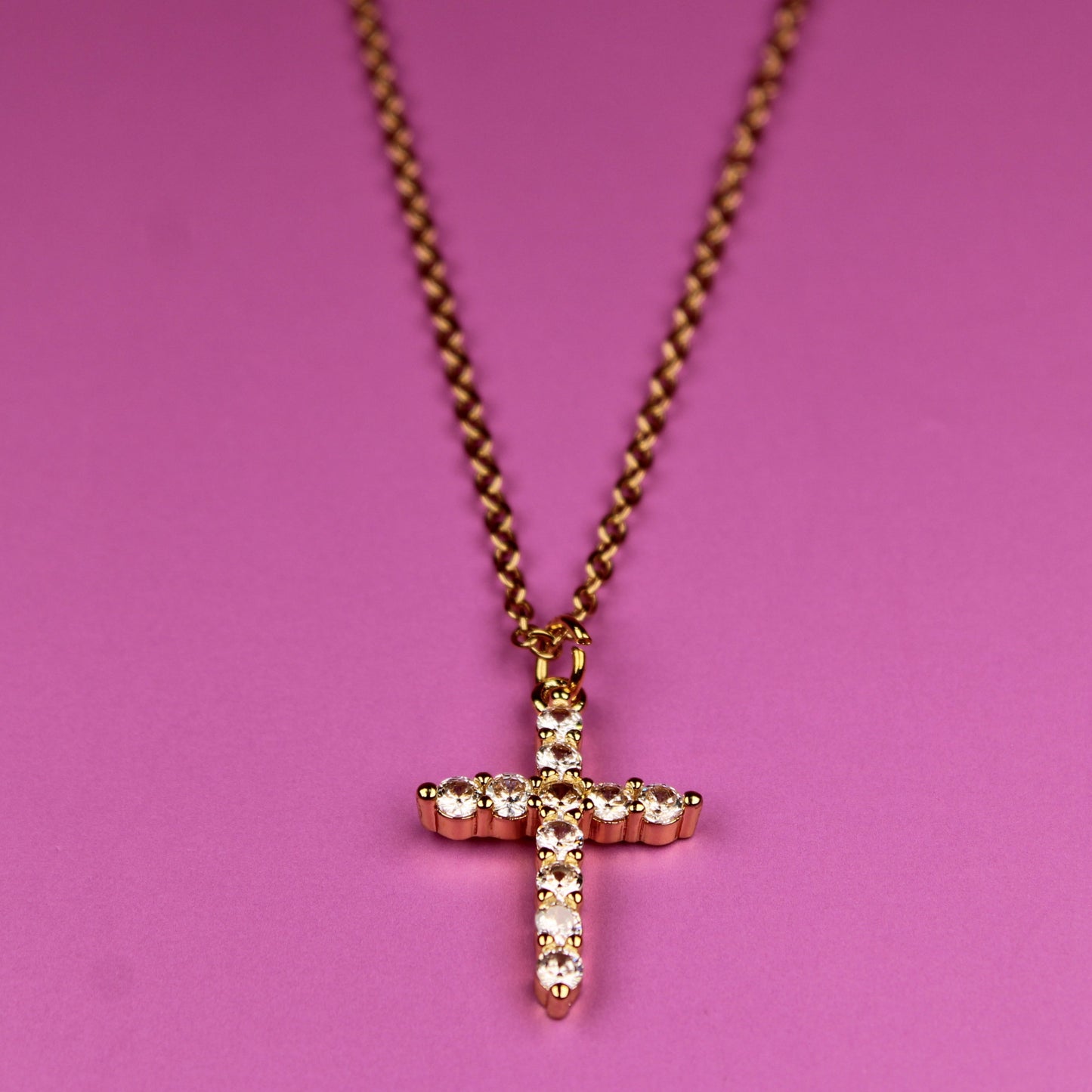Necklace with a cross pendant on a pink background