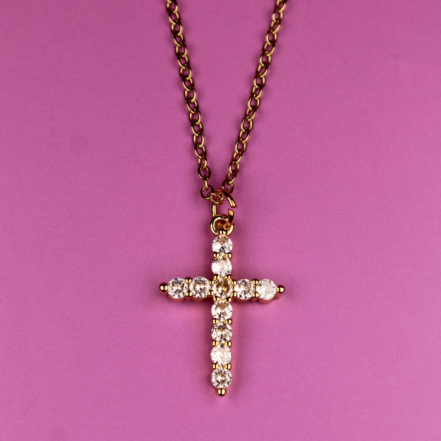 Cross necklace with diamonds on a pink background