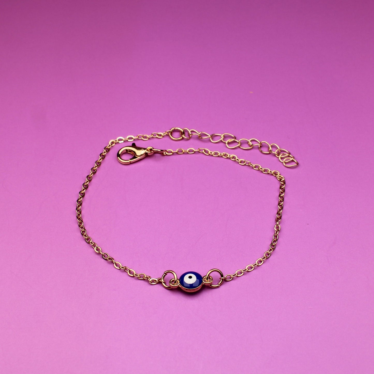 Gold bracelet with a purple gemstone on a pink background