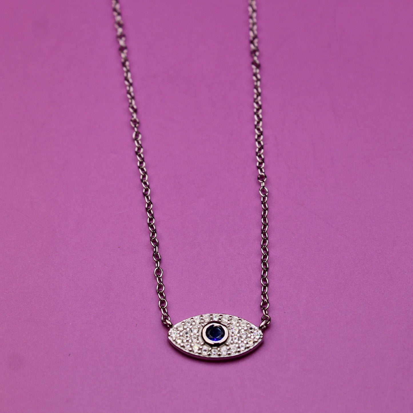 Necklace with an eye-shaped pendant on a pink background