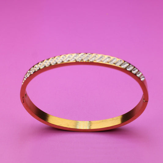 Gold bracelet with diamonds on a pink background