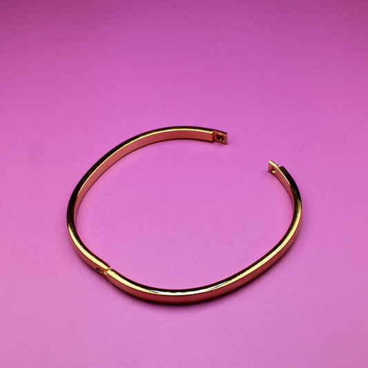 Gold bangle on a pink background