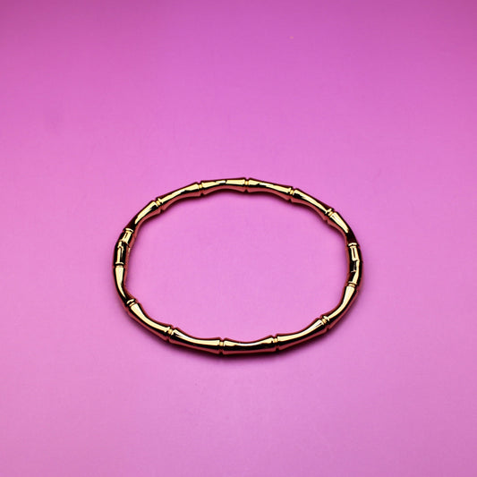 Gold bracelet on a pink background