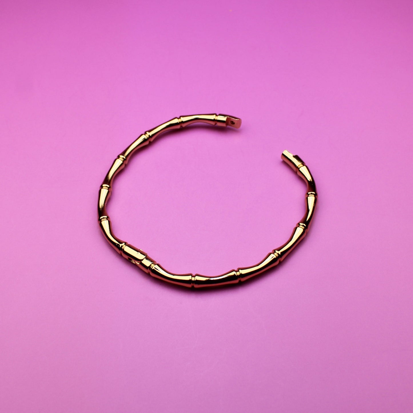 Gold bracelet on a pink background