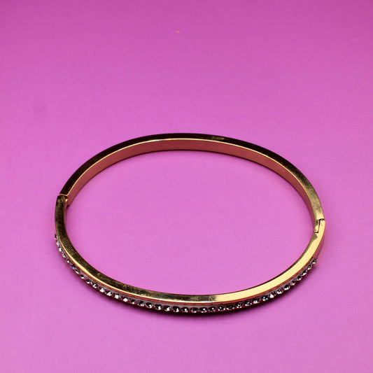 Gold bracelet on a pink background