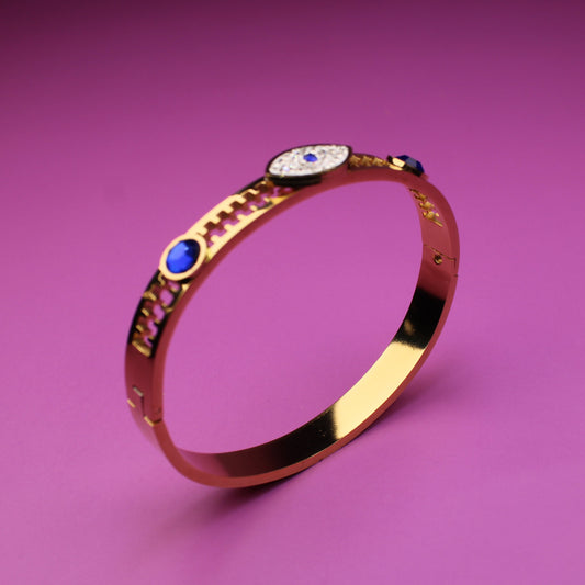 Gold bracelet with gemstones on a pink background