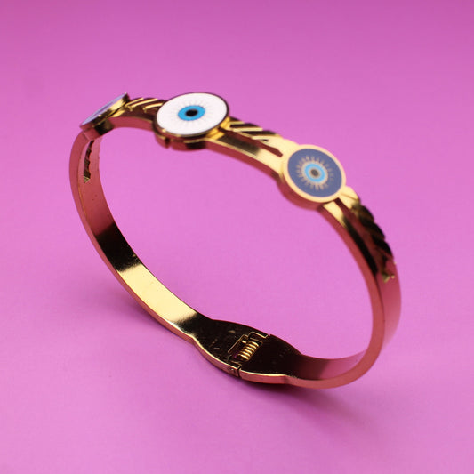 Gold bracelet with blue gemstones on a pink background