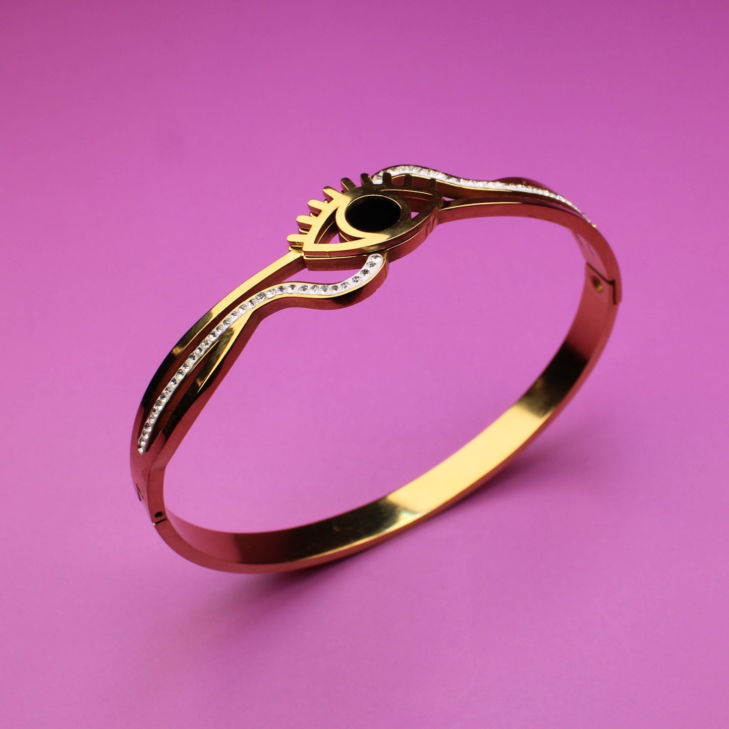 Gold ring with a green gemstone on a pink background