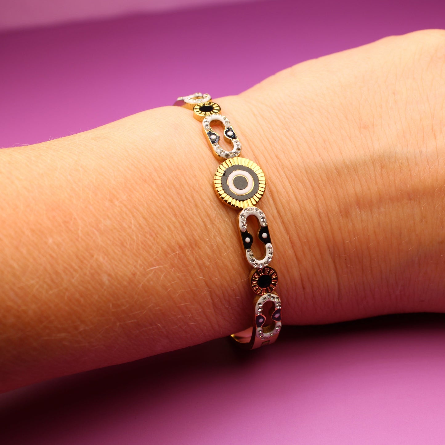 Hand wearing a gold bracelet on a purple background