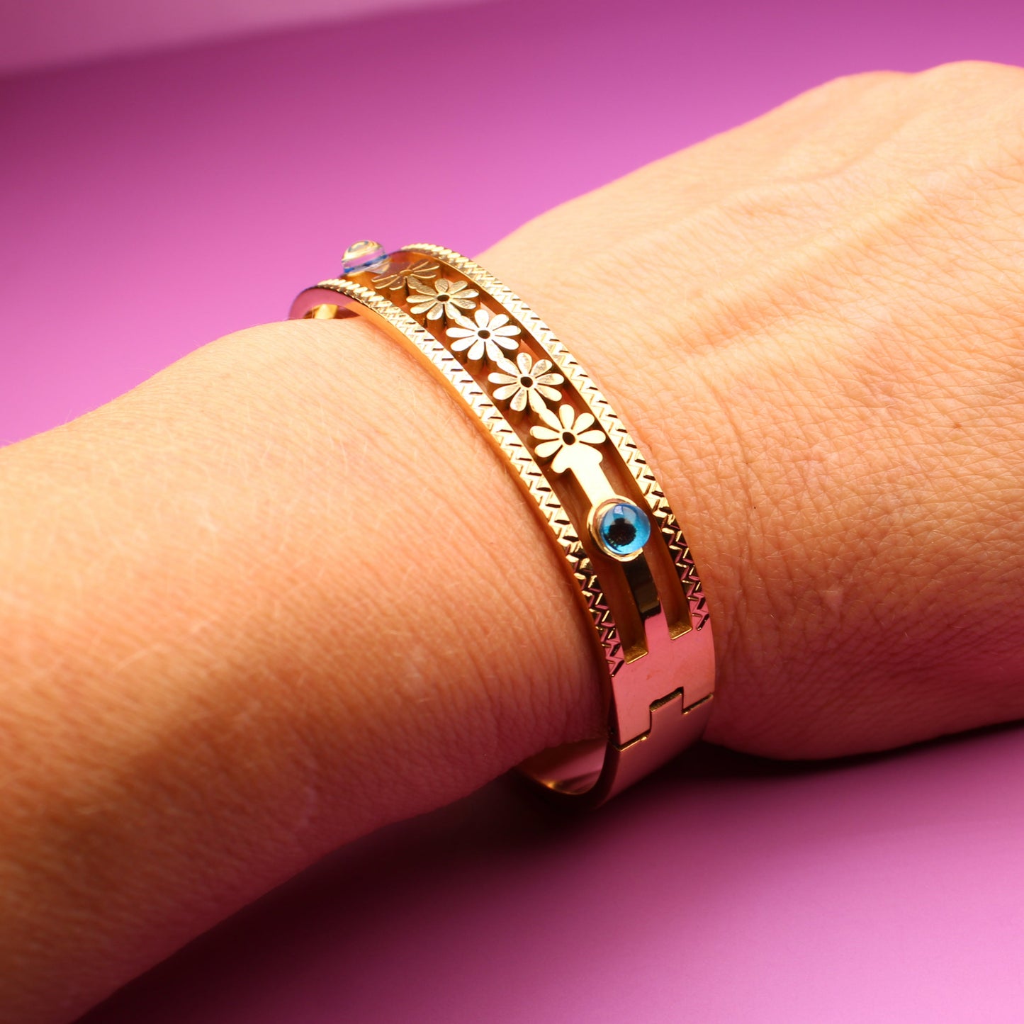 Hand wearing a gold bracelet with a purple background