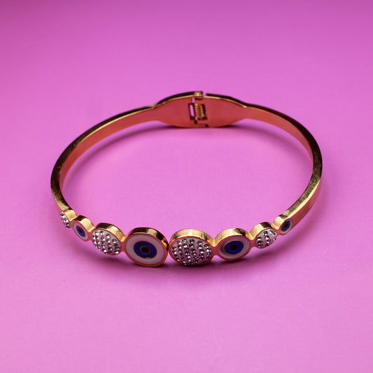 Gold bracelet with gemstones on a pink background