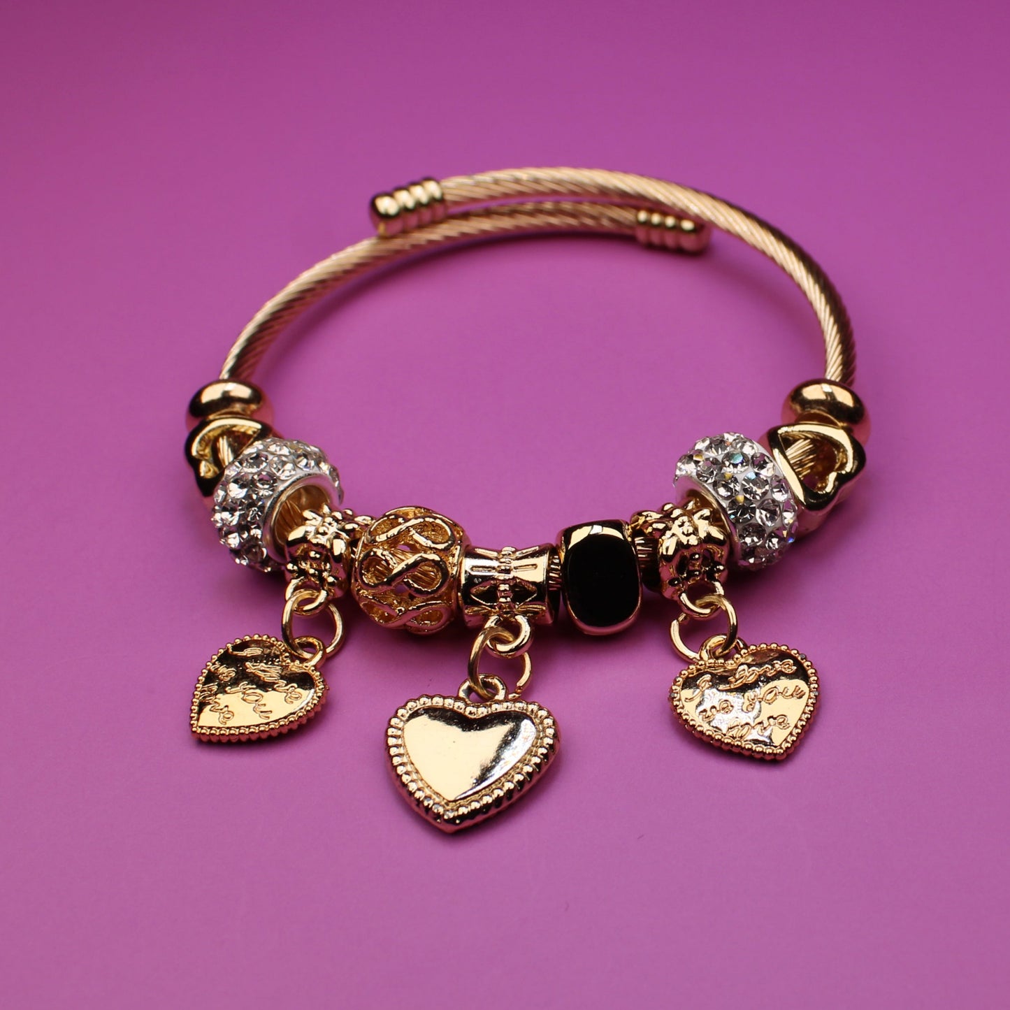Gold bracelet with charms on a pink background