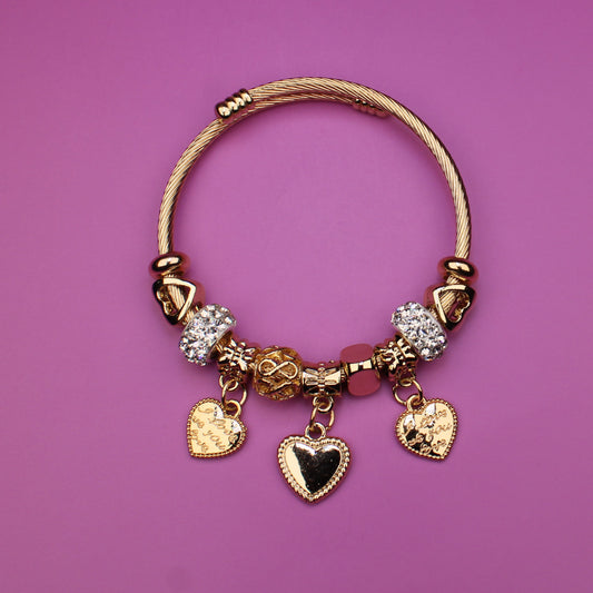 Gold bracelet with charms on a pink background