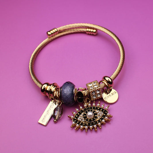 Gold bracelet with charms on a pink background