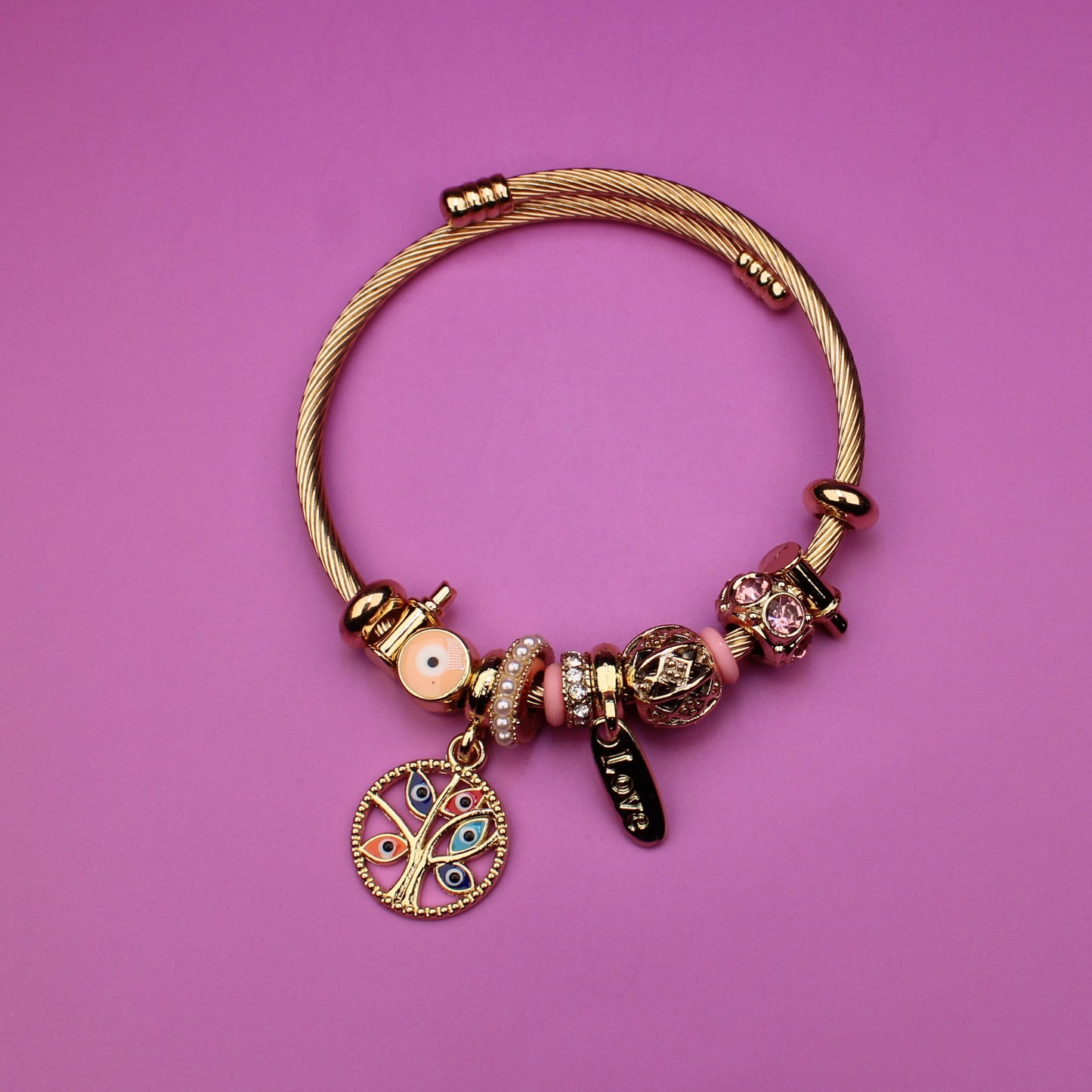 Gold bracelet with charms on a pink background