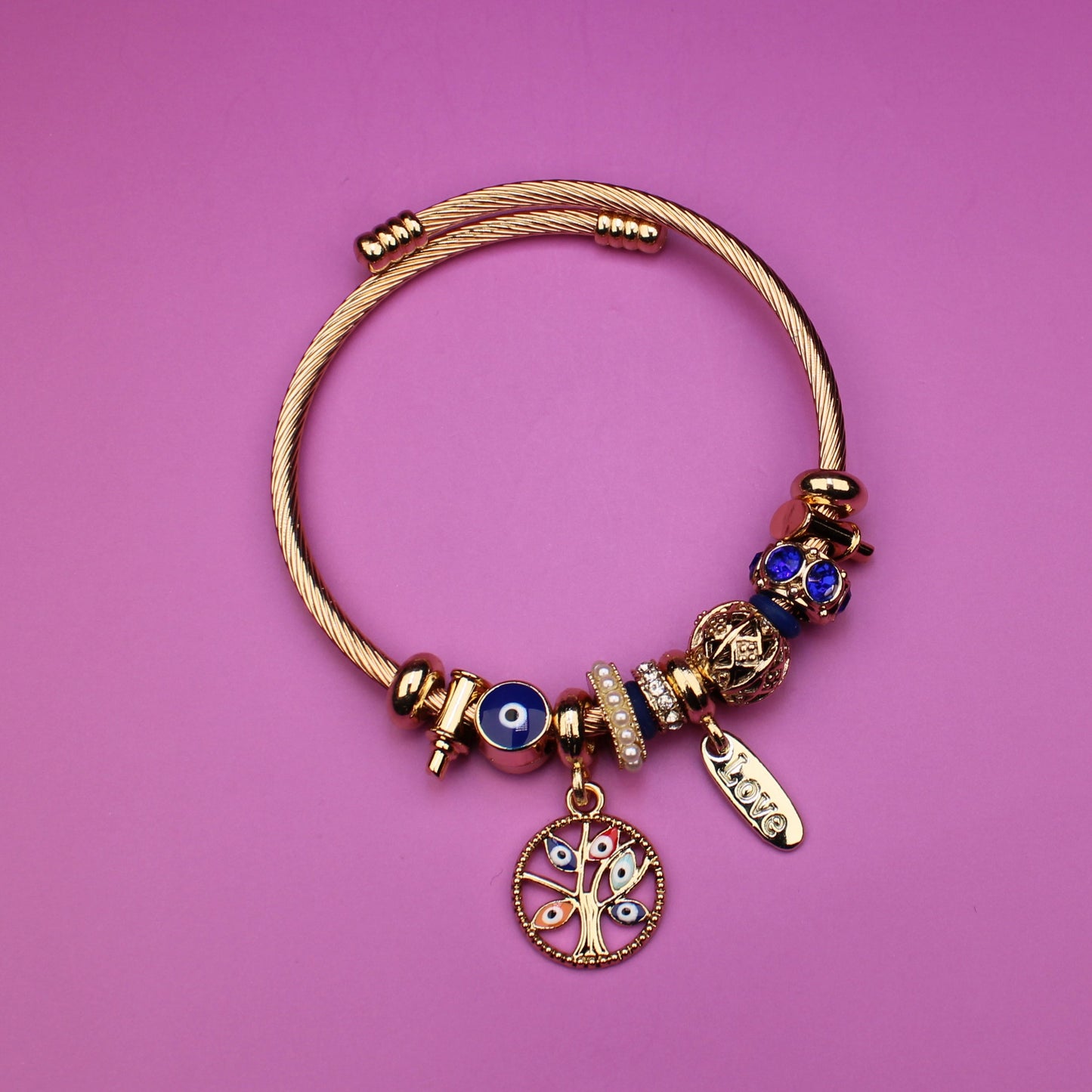 Gold bracelet with charms on a pink background