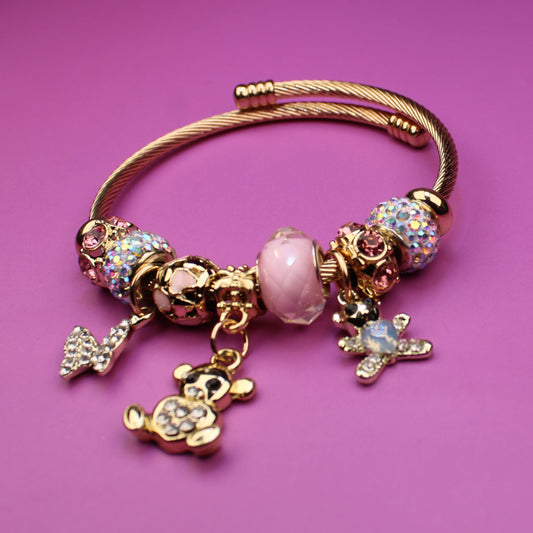 Gold bracelet with charms on a pink background