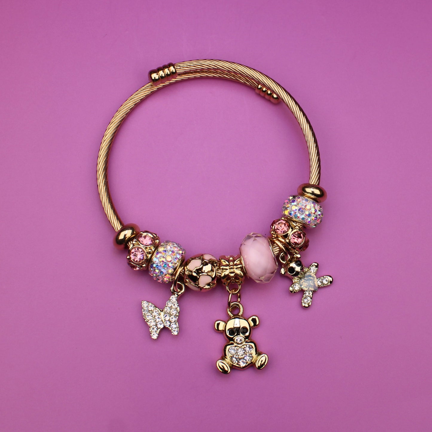 Gold bracelet with charms on a pink background