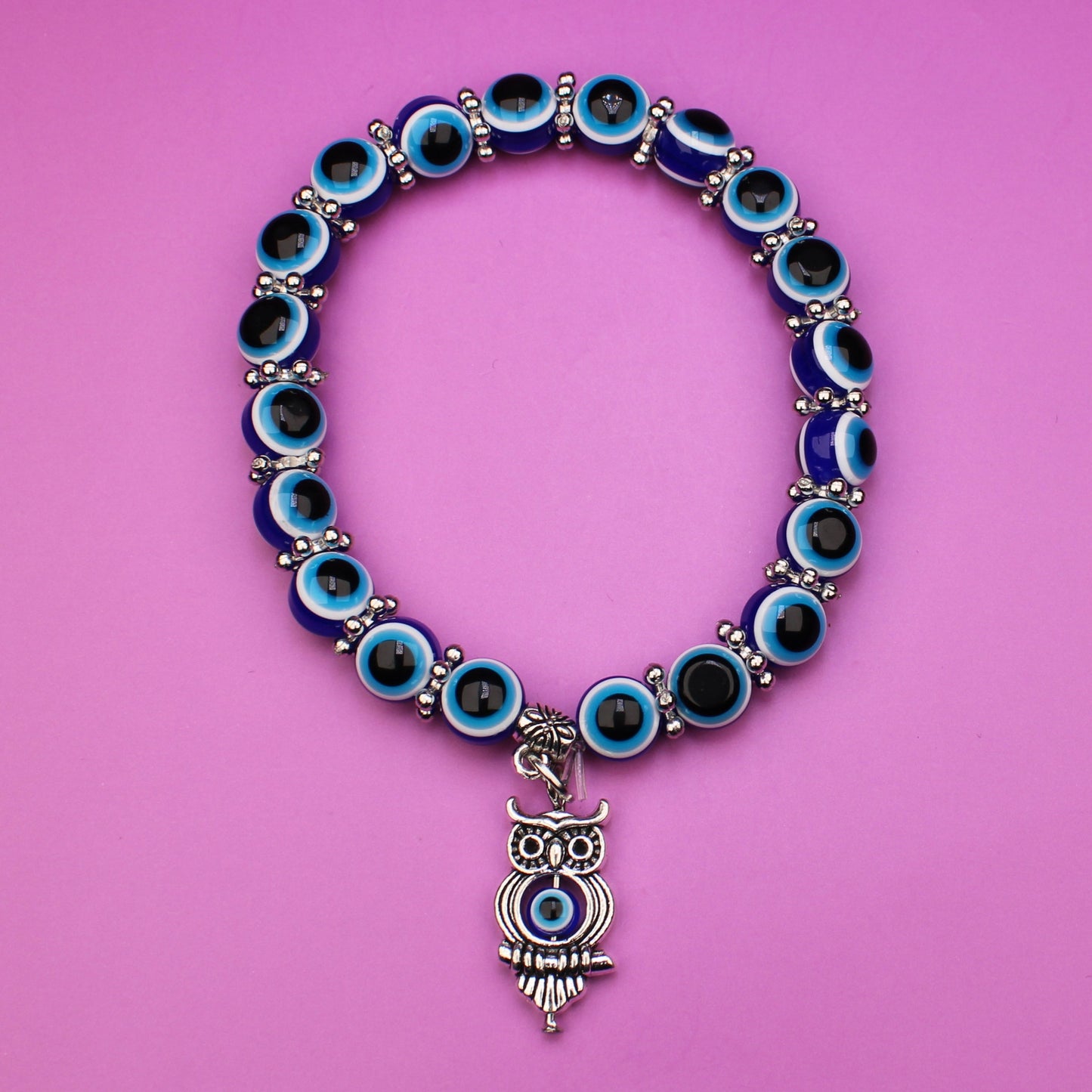 Bracelet with blue beads and an owl charm on a pink background