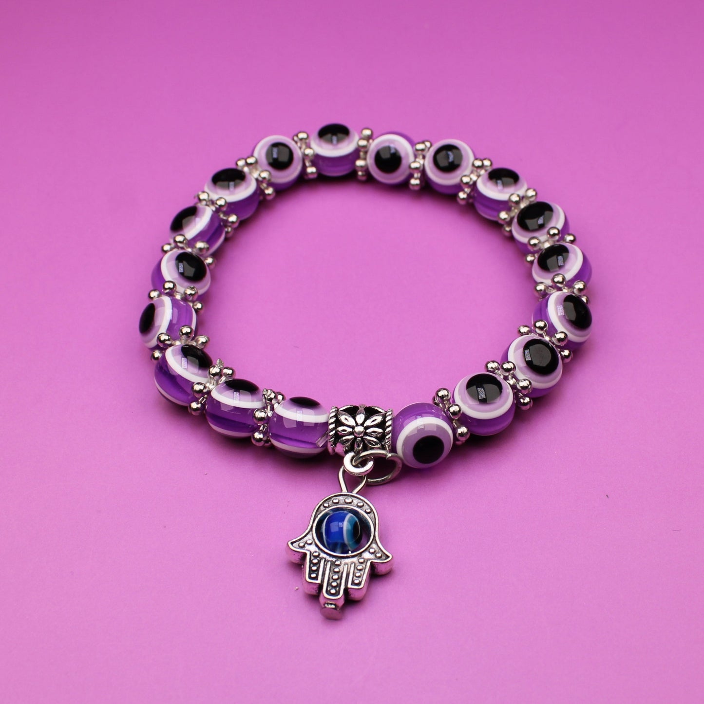 Bracelet with a hamsa charm on a pink background