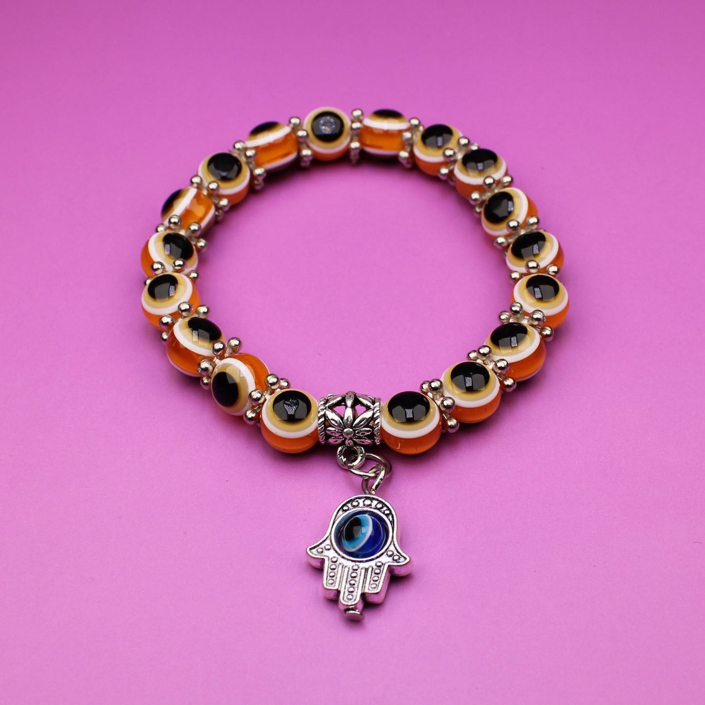 Bracelet with colorful beads and a hamsa charm on a pink background