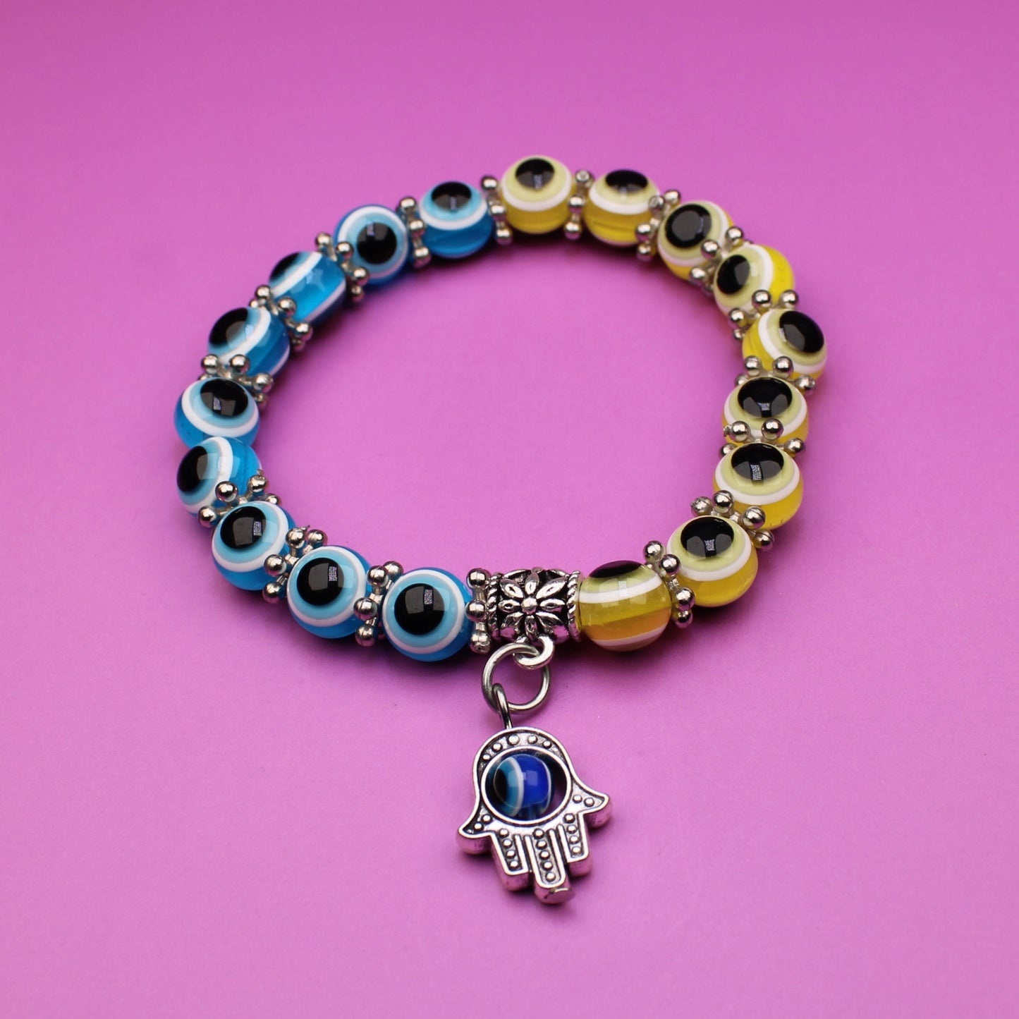 Colorful beaded bracelet with a hamsa charm on a pink background