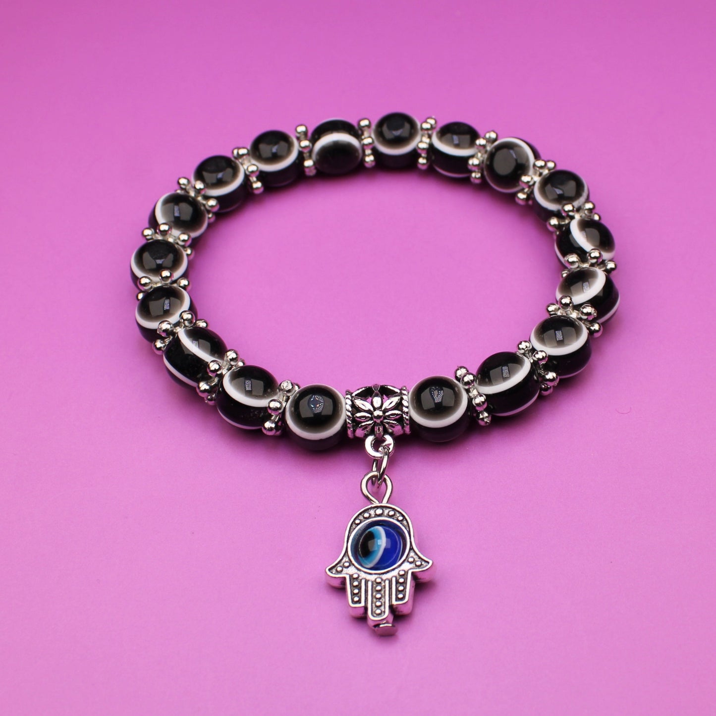 Bracelet with a hamsa charm on a pink background