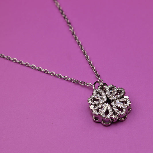 Silver necklace with a floral pendant on a pink background