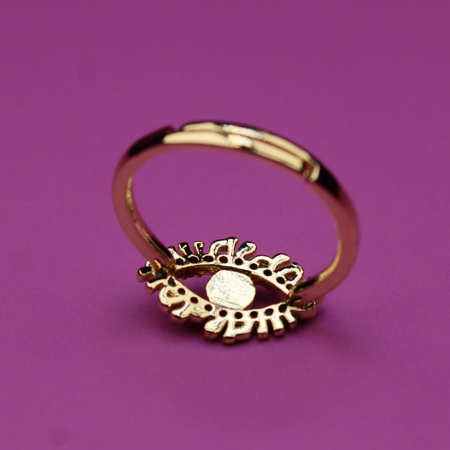 Gold ring with a decorative design on a purple background