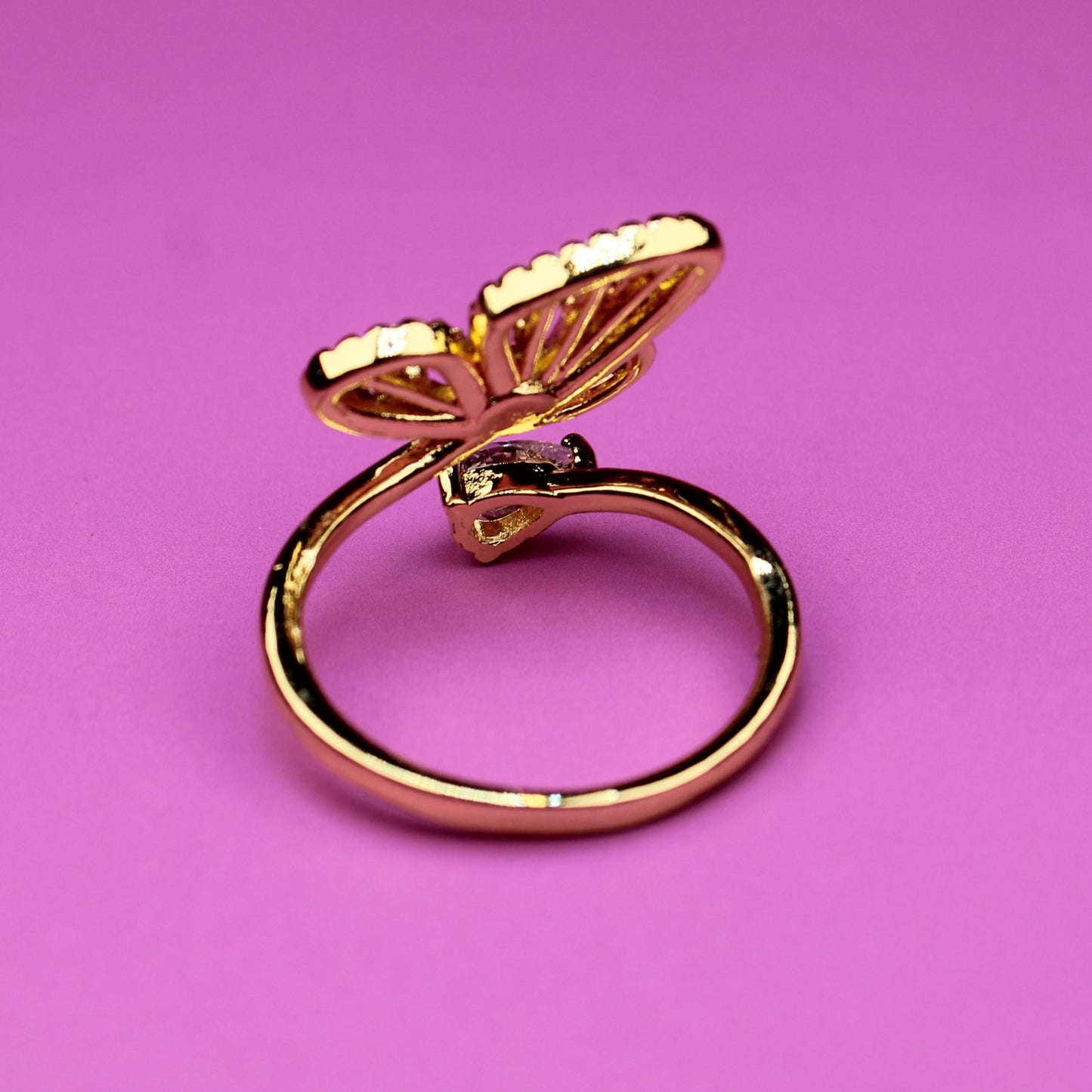 Gold butterfly ring on a pink background
