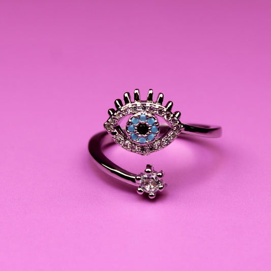 Silver ring with eye design on a pink background
