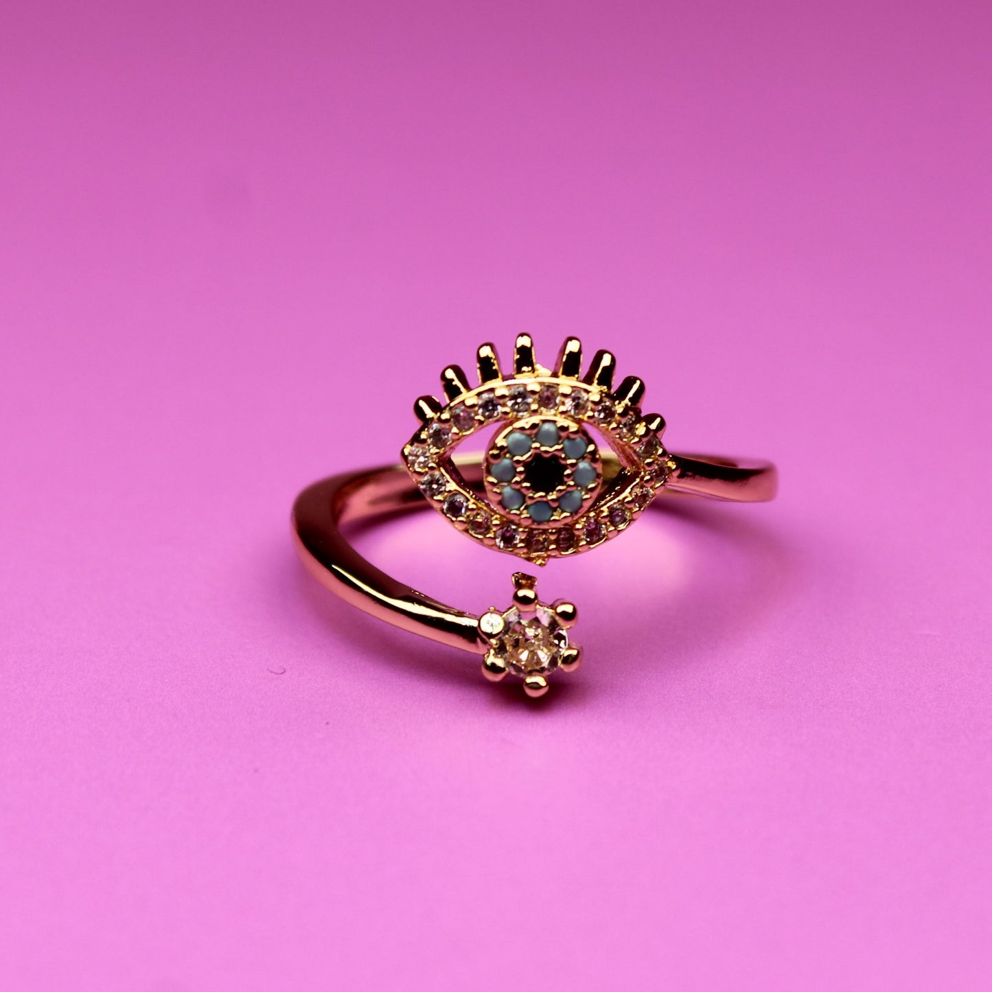 Rose gold ring with gemstones on a pink background