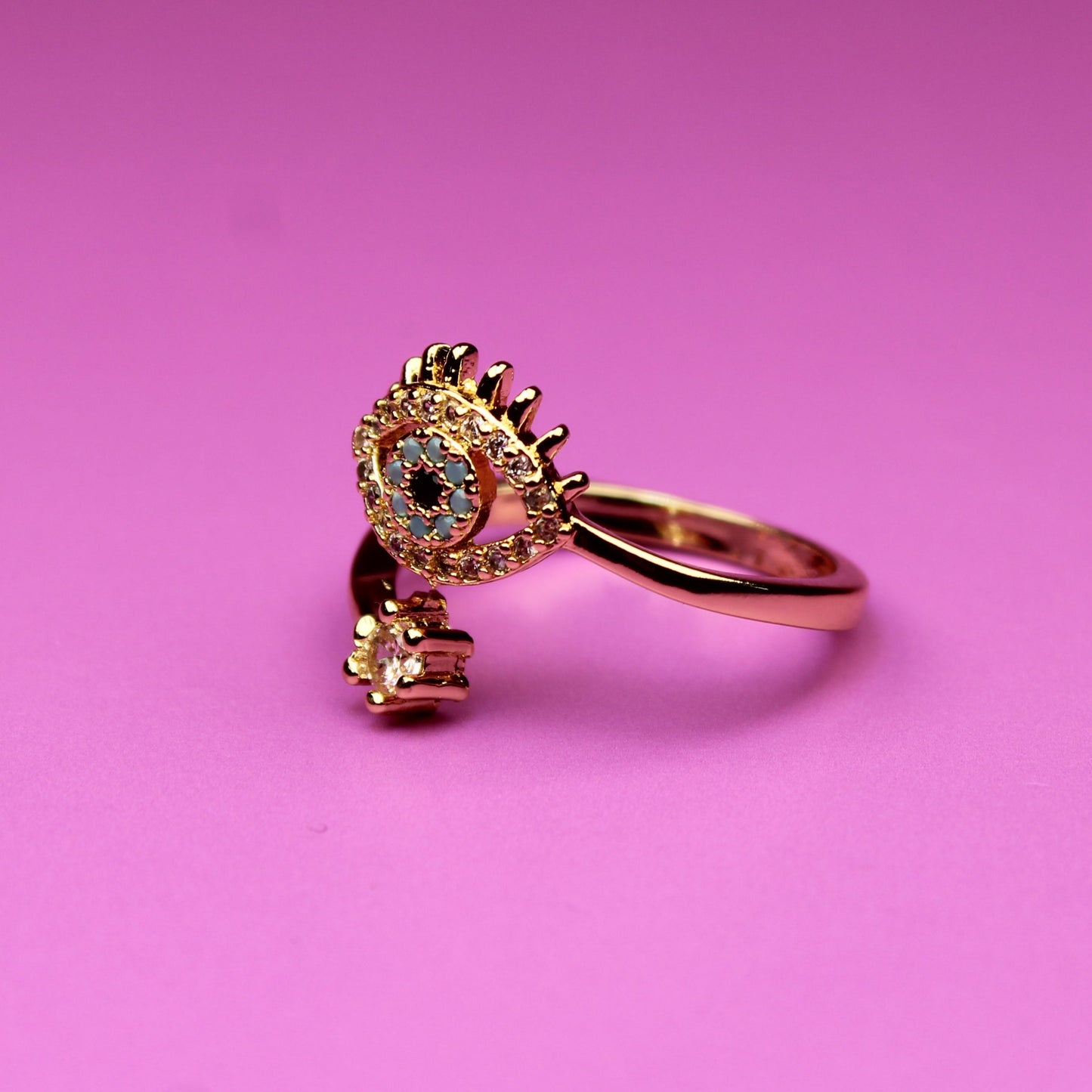 Gold ring with a heart-shaped gem on a pink background