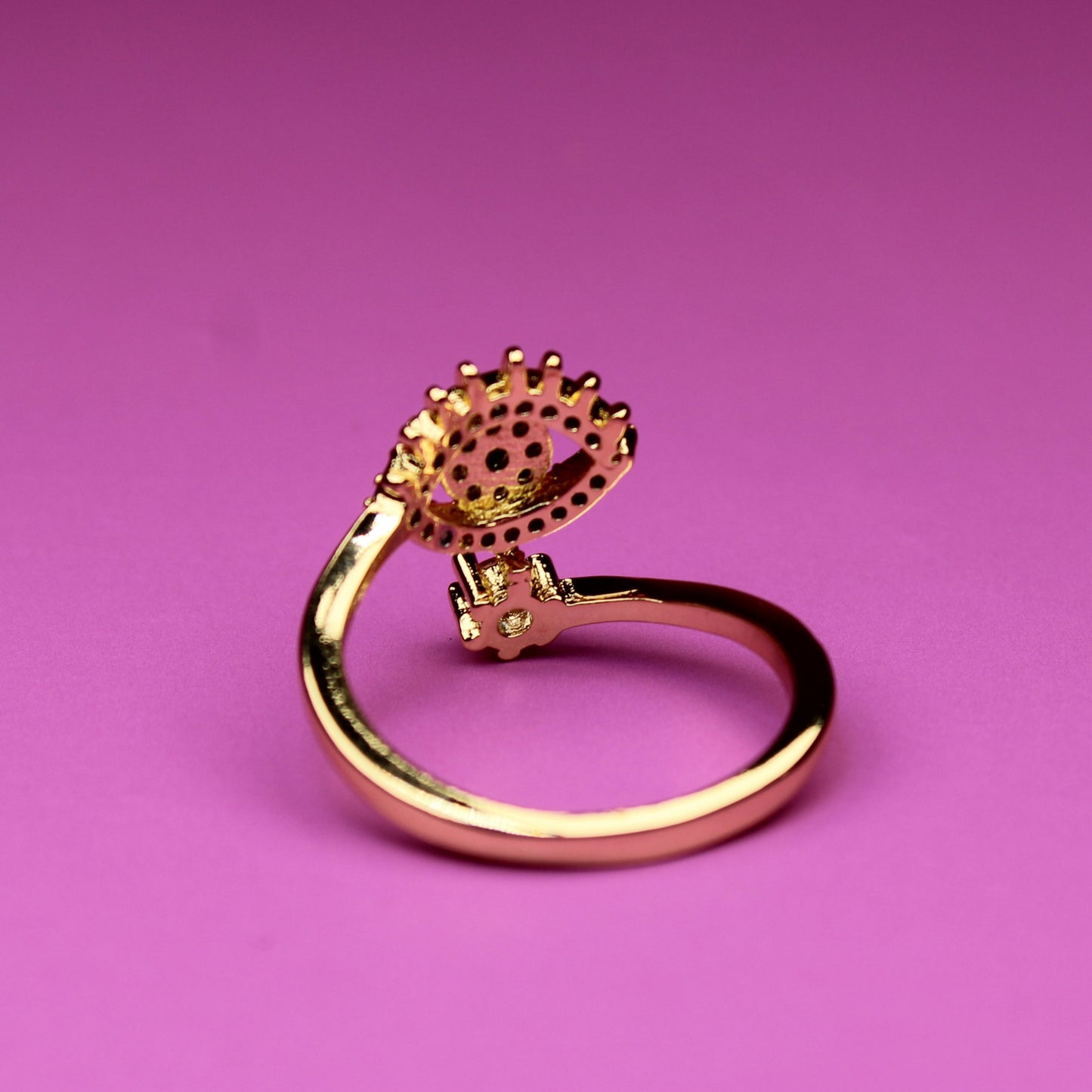 Gold ring with a textured top on a pink background