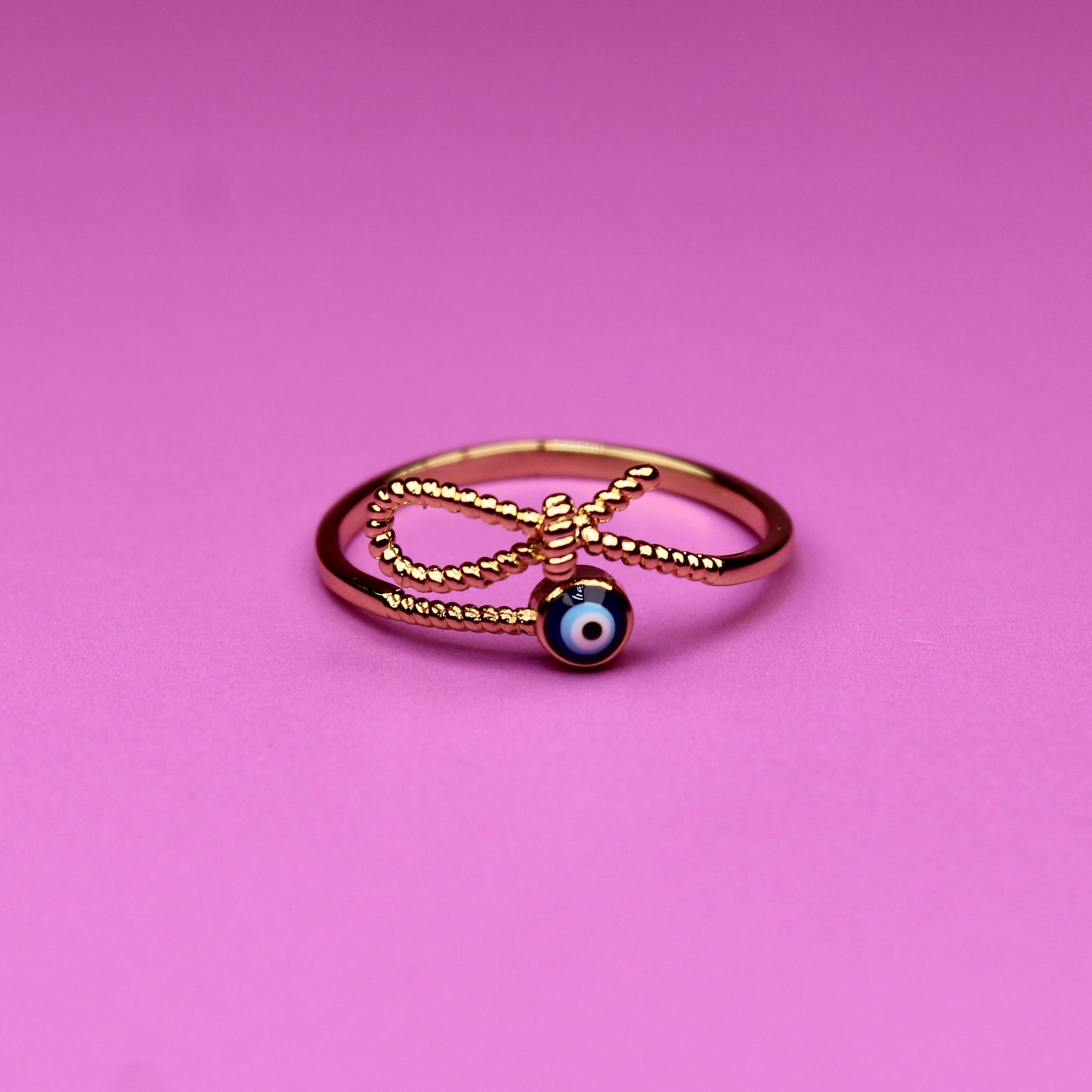 Gold ring with a blue gemstone on a pink background