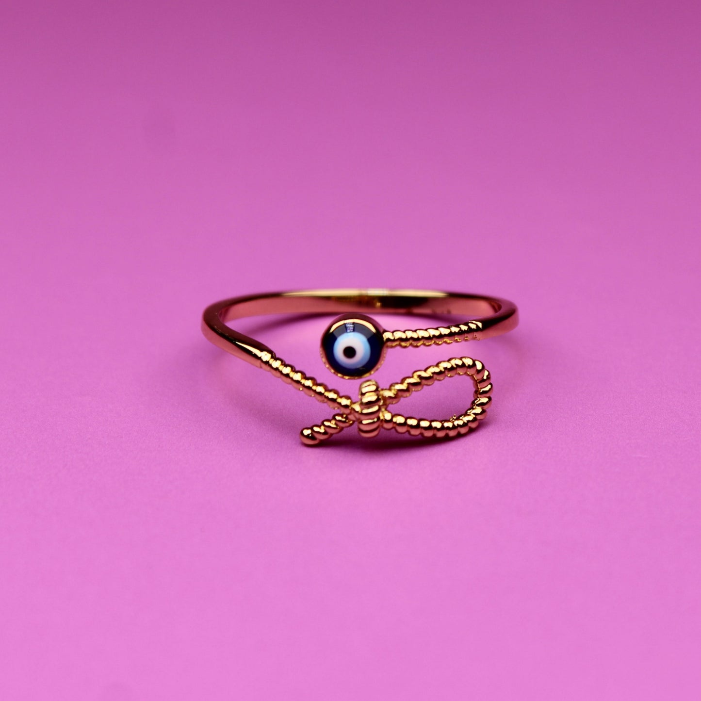 Gold ring with a black gemstone on a pink background