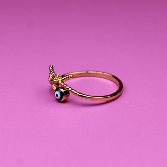 Gold ring with a small green gem on a pink background