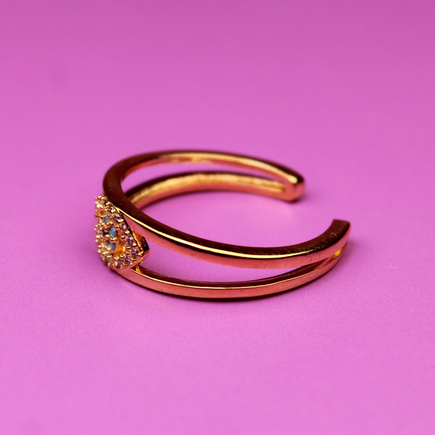 Gold ring with gemstones on a pink background