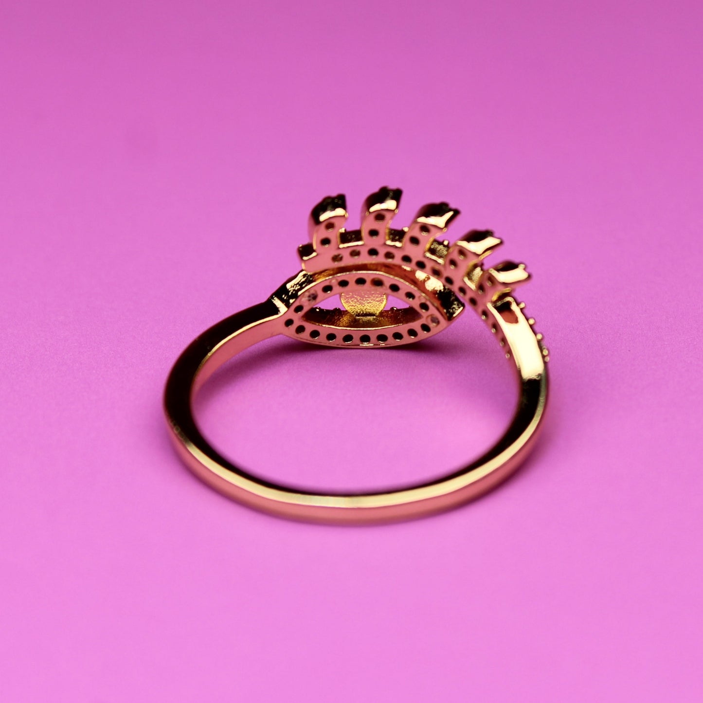 Gold ring with decorative design on a pink background