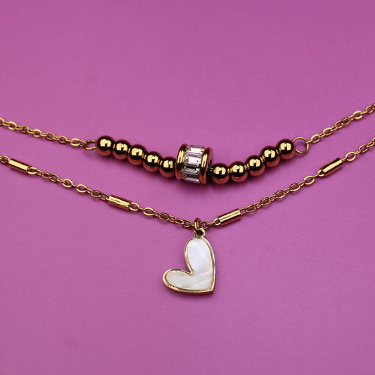 Necklace with heart pendant and beaded chain on a pink background