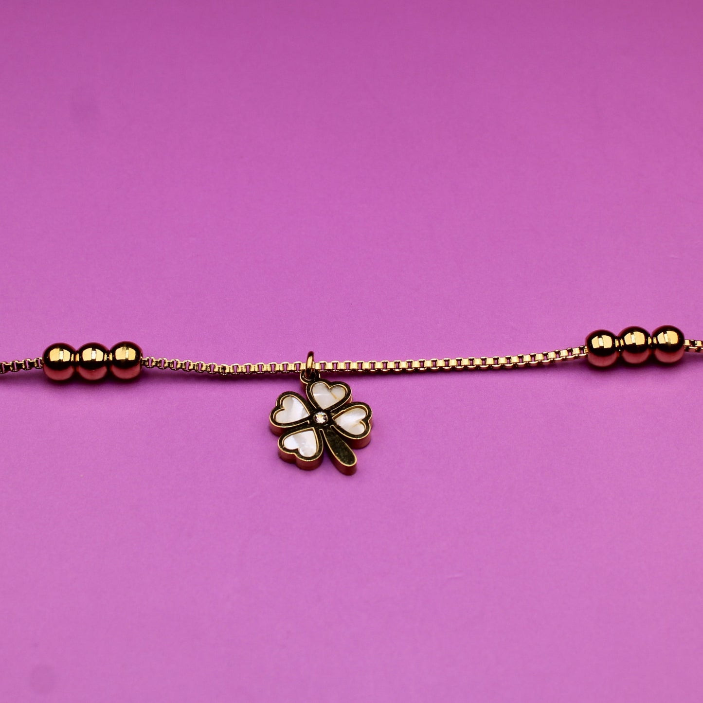 Bracelet with a clover charm on a pink background