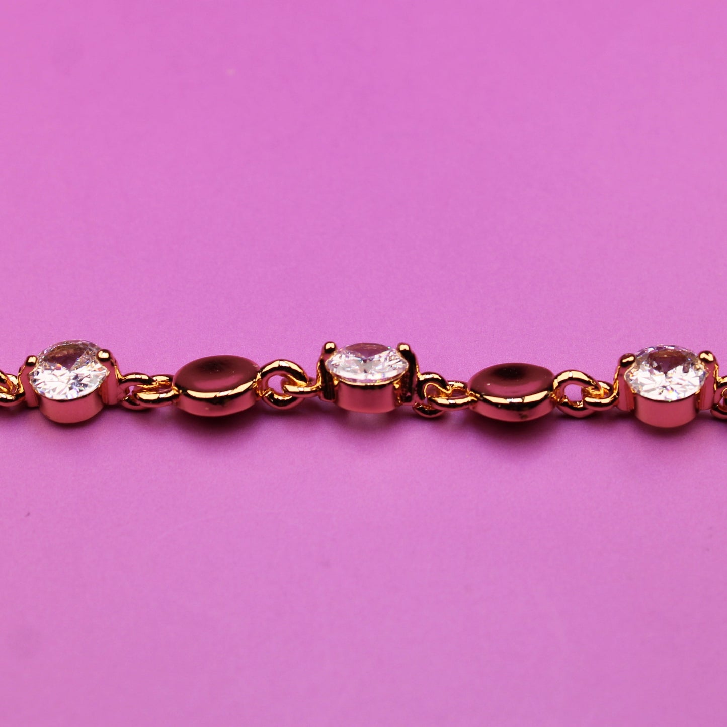 Gold bracelet with small diamonds on a pink background