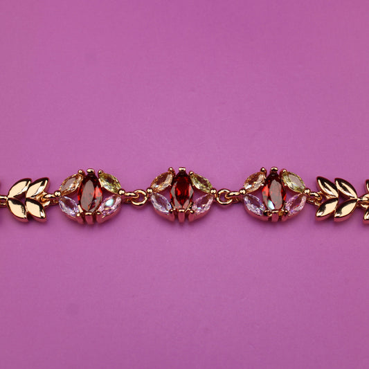 Gold bracelet with red gemstones on a purple background