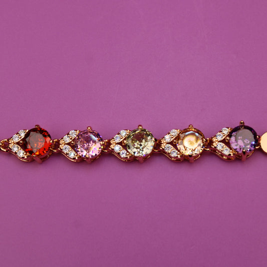 Gold bracelet with multicolored gemstones on a purple background