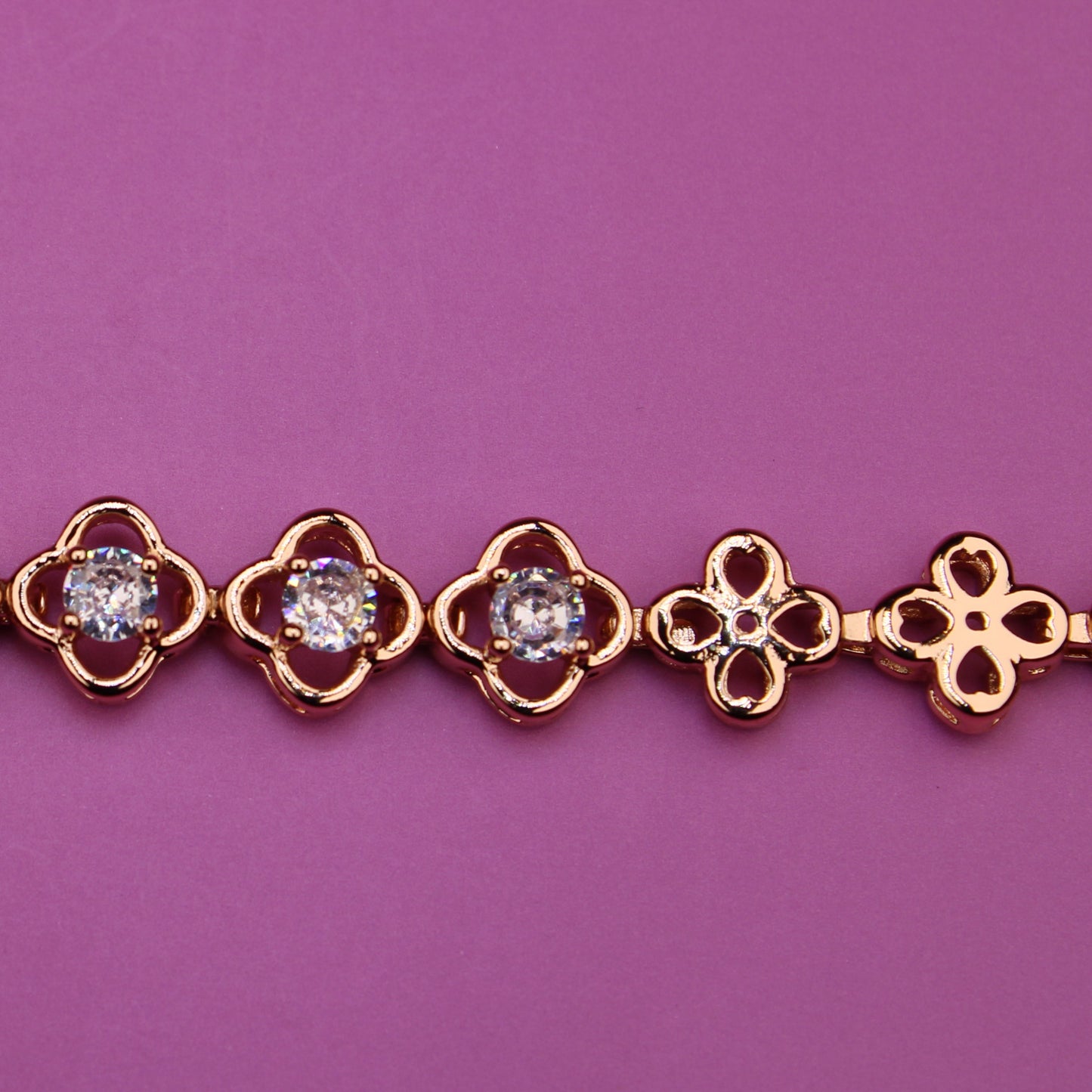 Gold bracelet with diamond accents on a purple background