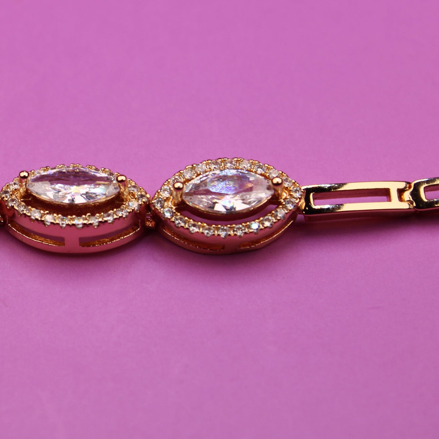 Rose gold bracelet with gemstones on a pink background