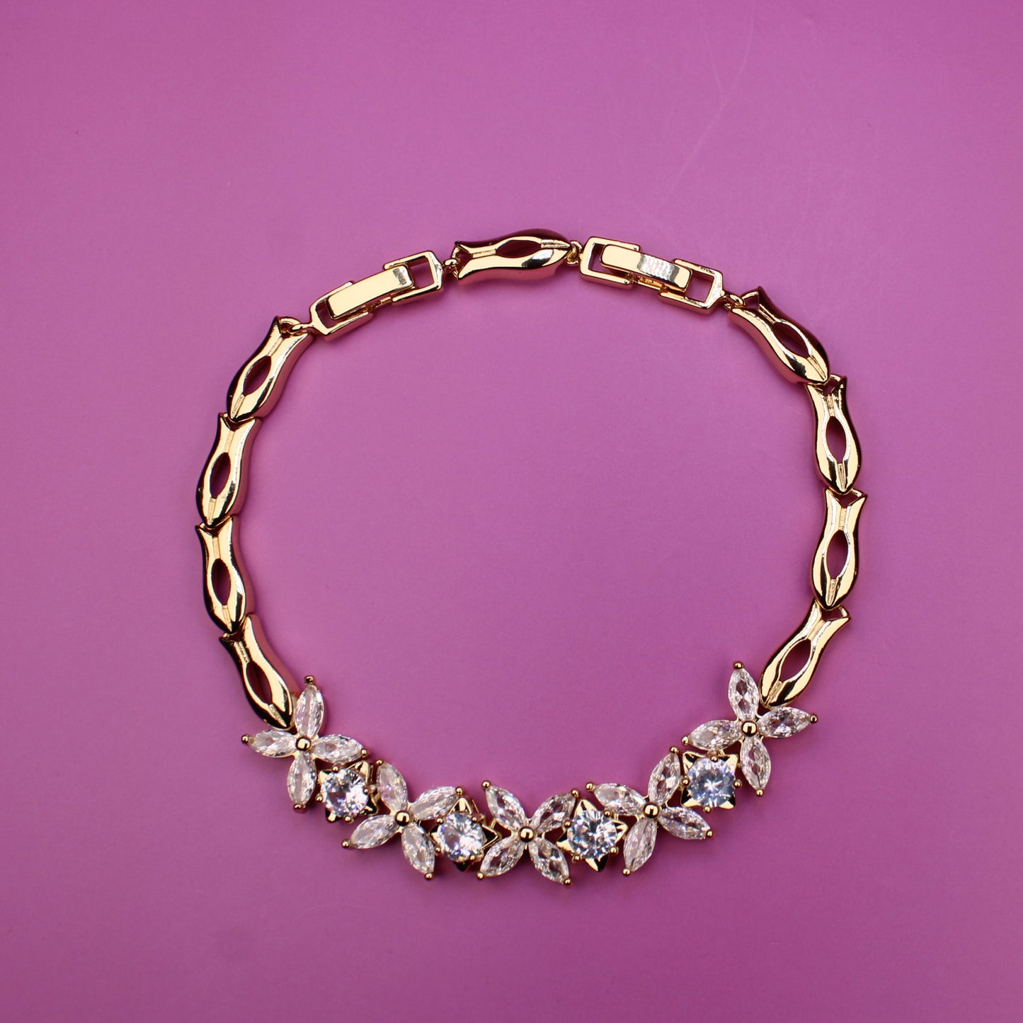 Gold necklace with floral design on a pink background